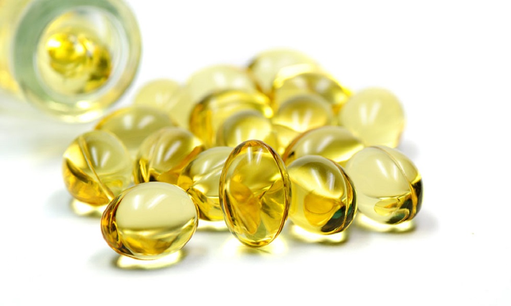 Cluster of golden oil-filled capsules on a white surface, glossy yellow tones, clean and clinical mood